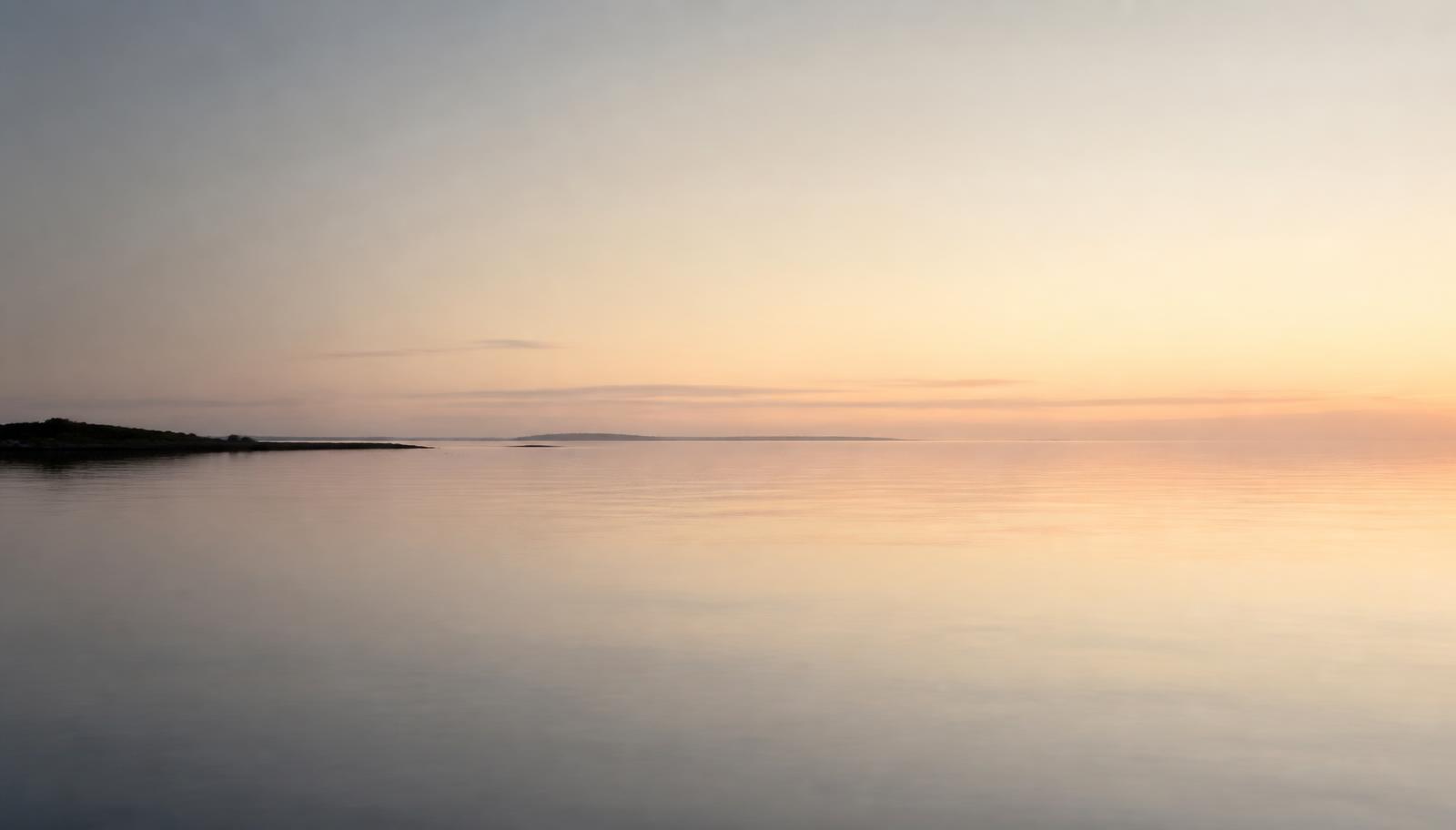 Stilla hav som möter en ljus himmel vid horisonten i nordiskt gryningsljus