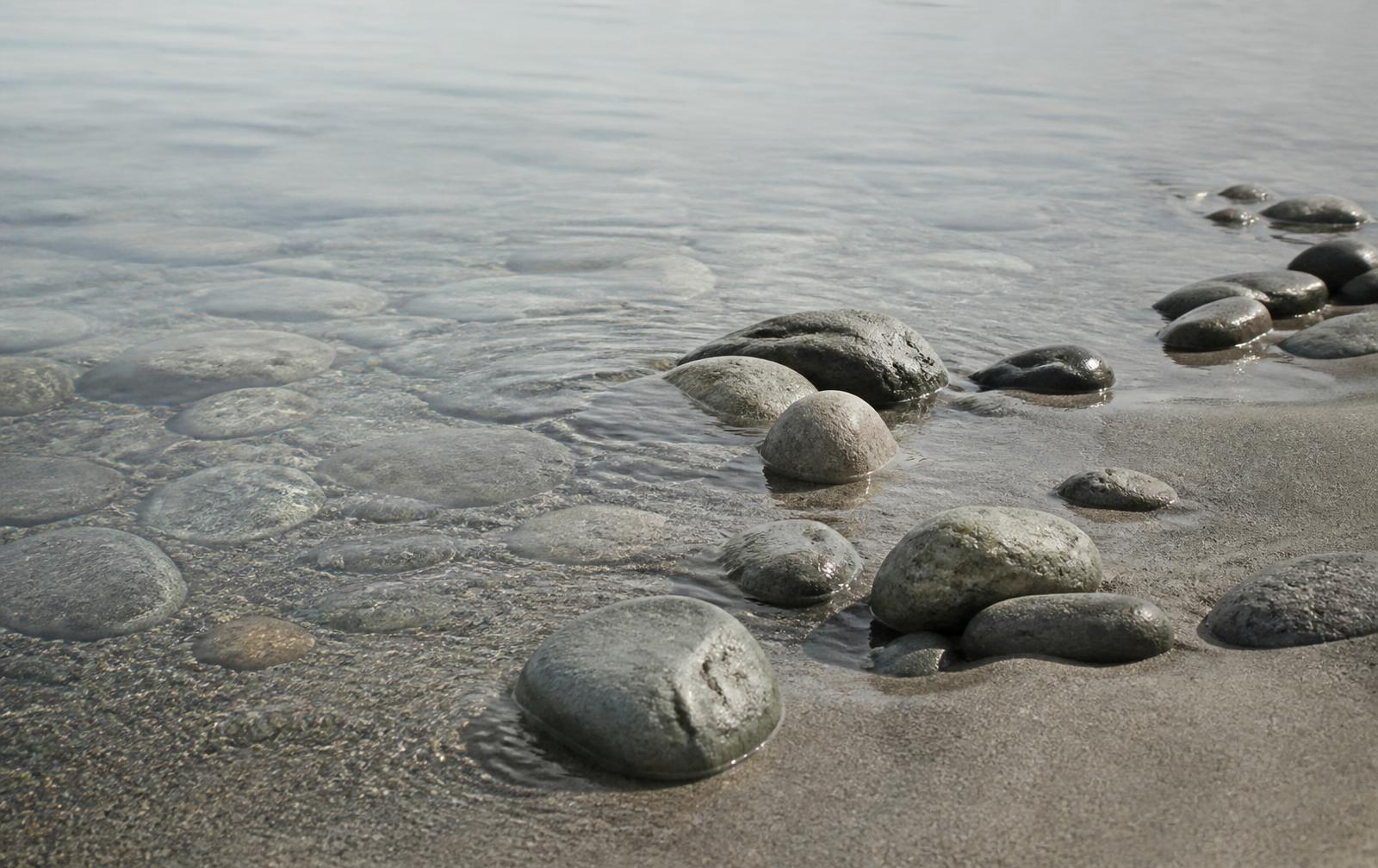 Släta stenar i grunt, stilla vatten vid en nordisk strandkant